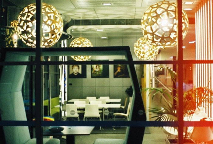 Office lounge interior, golden geometric pendant lamps, Ed Sheeran portraits, 35mm