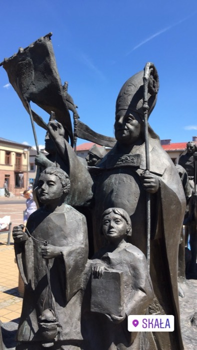 Bronze statue of bishop with children on sunny town square