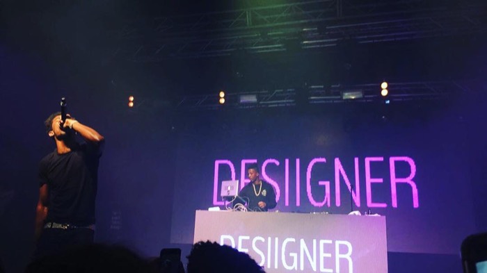 Desiigner rapping on stage, purple lights, DJ behind name screens