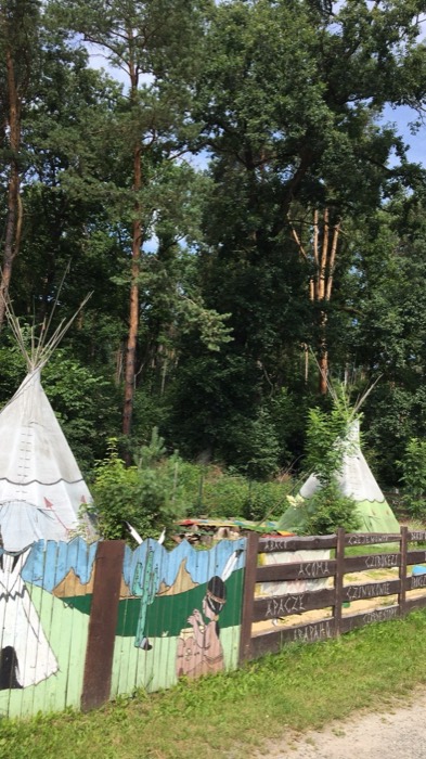 Teepees behind fence painted with Polish names of Native tribes