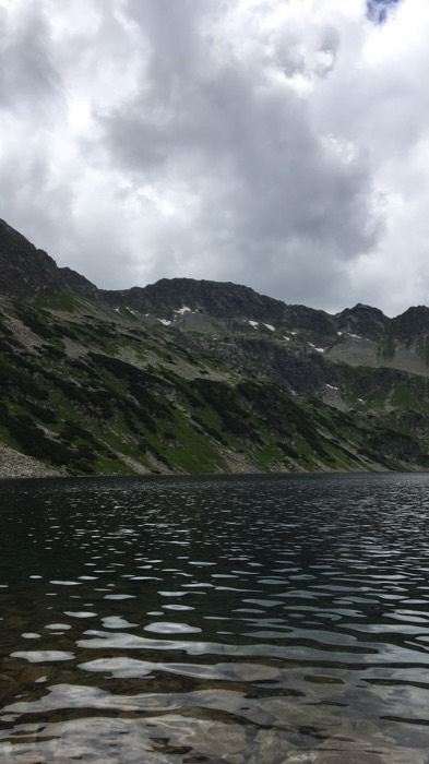 Moody dark mountain lake ringed by Tatra peaks and clouds