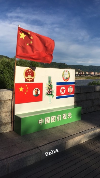Tumen border tourism sign with Mao and Kim Il-sung portraits, Chinese flag