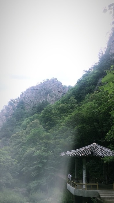 Misty green mountain crags with traditional pavilion, half frame washed out