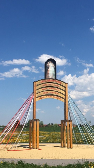 Divine Mercy wooden arch monument with ribbons under deep blue sky