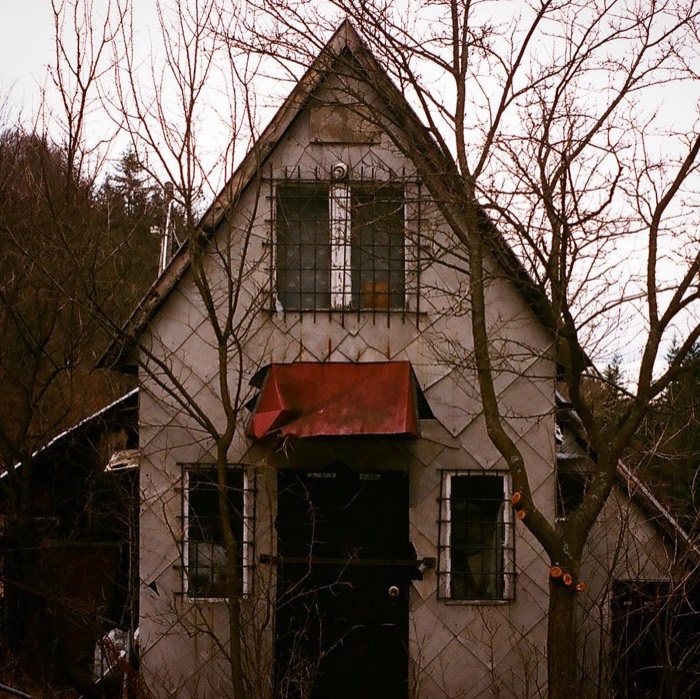 Creepy gothic cottage with barred windows and red awning, 35mm