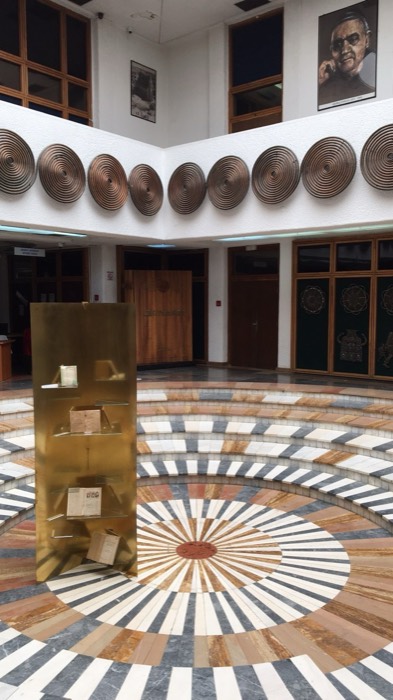 Circular hall with radial marble floor mosaic and copper spiral wall discs
