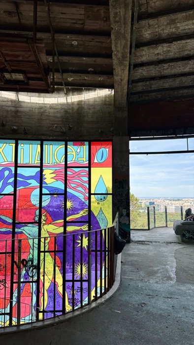 Colorful stained-glass mural and city view inside abandoned rotunda