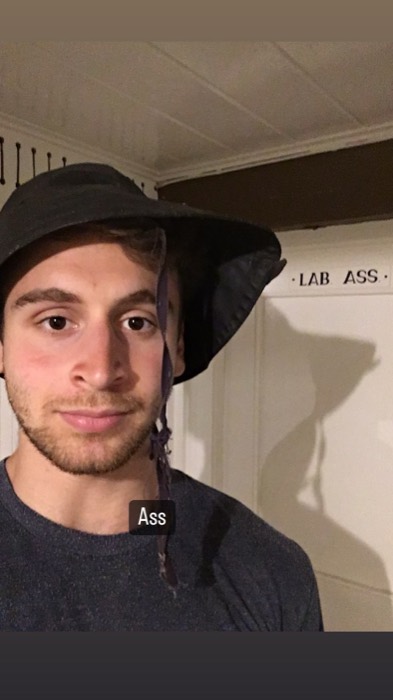 Joshua: selfie in floppy hat beside ship's 'LAB. ASS.' sign