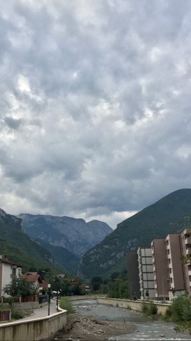 River through Peja town with dramatic Rugova canyon mountains behind