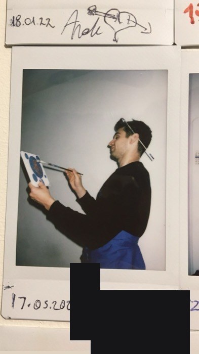 Joshua: dated polaroid of him painting folk tile, brush balanced on head