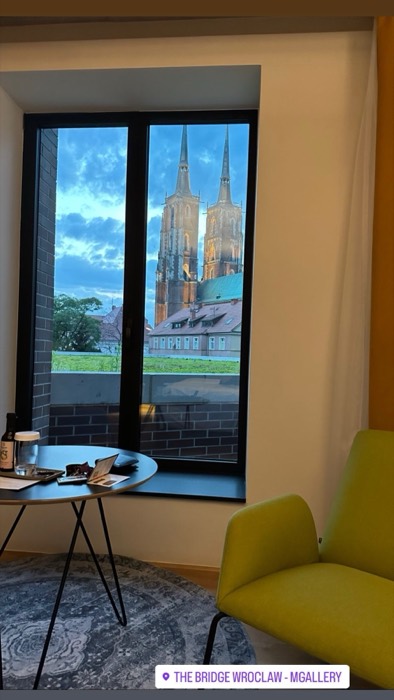 Hotel room window framing Wroclaw cathedral spires at dusk