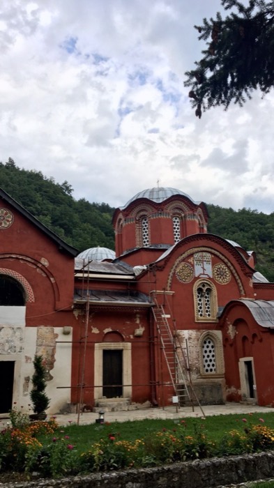 Red-walled Patriarchate of Pec monastery church with domes and flower garden
