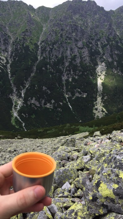 Thermos cup toast on boulder field facing sheer Tatra cliffs