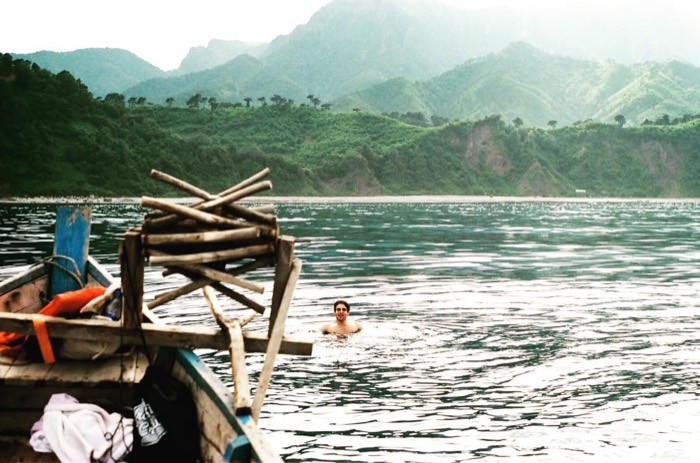 Exact duplicate of Joshua swimming alone beside wooden boat