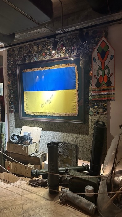 Signed Ukrainian flag, military patches and ammo crates, war-themed bunker bar