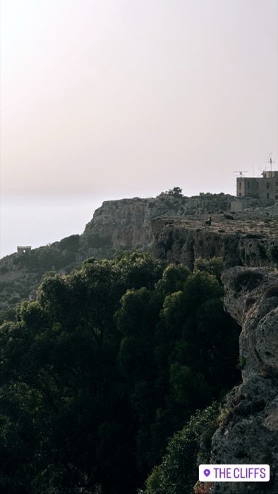 Dingli Cliffs at hazy dusk, lone goat silhouetted on ridge