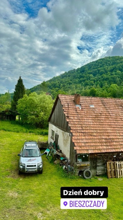 Rustic farmhouse with Land Rover and forested hills, vacation start