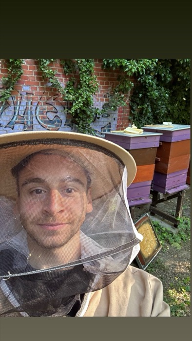 Joshua: beekeeper veil selfie beside colorful hives at urban apiary