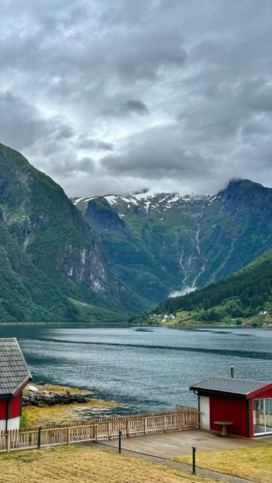 Fjord panorama with red boathouses, waterfalls and snow-capped peaks