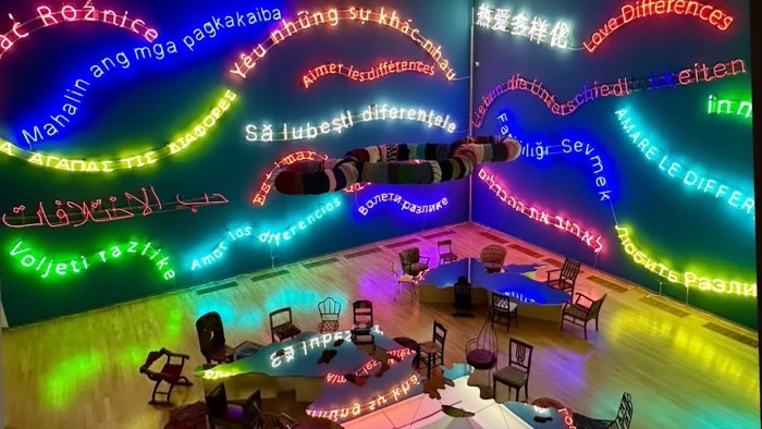 Neon installation: 'love differences' glowing in many languages across dark ceiling
