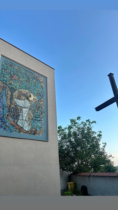 Mid-century mosaic artwork on modernist church wall beside cross