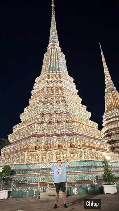 Joshua: arms raised triumphantly before giant Wat Pho chedi at night