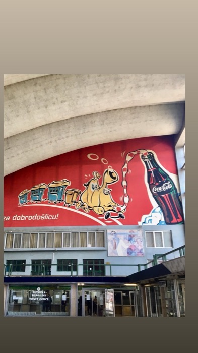 Retro Coca-Cola camel mural inside brutalist Sarajevo railway station hall