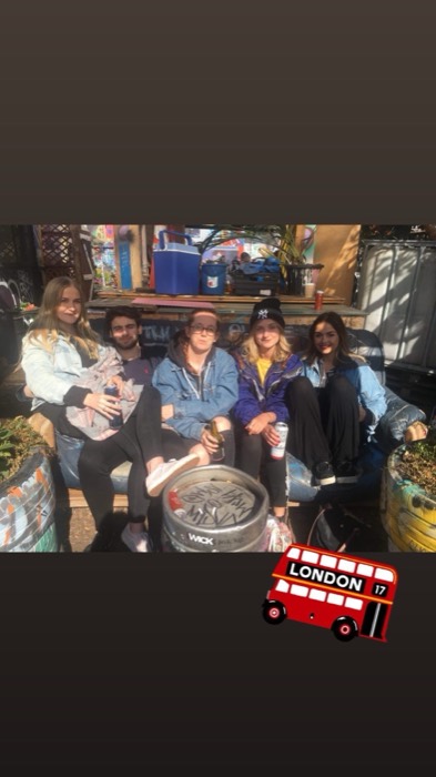 Five friends with beers on couch in graffiti community garden