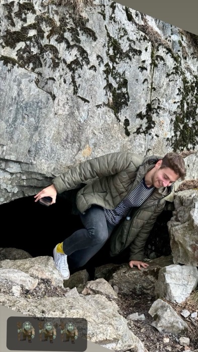 Joshua: grinning while climbing out of small cave entrance on hike
