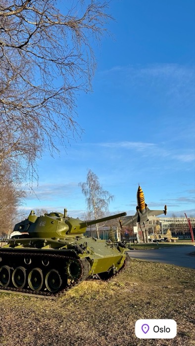 Tank and tiger-nosed fighter jet at outdoor military museum, blue sky