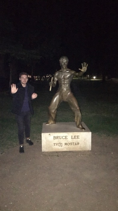 Joshua: mimicking Bruce Lee statue pose in Mostar park at night