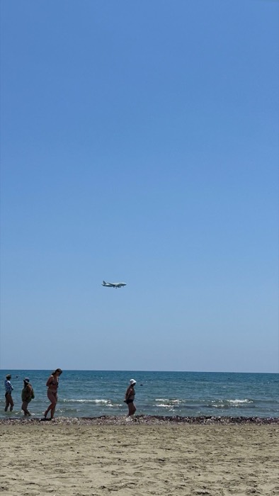 Airliner descending low over beach swimmers, famous plane-spotting shore