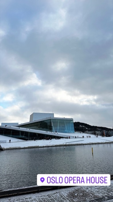 Snow-dusted Oslo Opera House sloping into the fjord, people walking roof