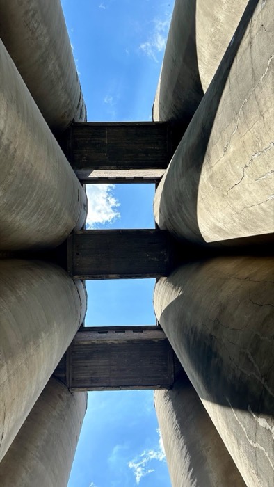Looking up between massive concrete grain silos joined by bridges