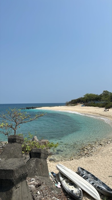 Turquoise crescent bay with white sand and kayaks ashore