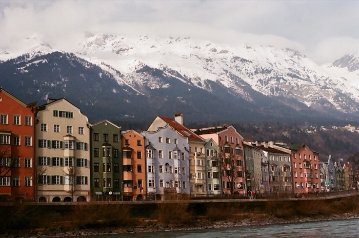 Colorful Mariahilf houses below snow-capped Alps along the Inn.