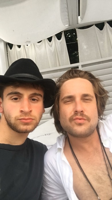 Joshua: cowboy hat, selfie with bearded friend under white canopy.