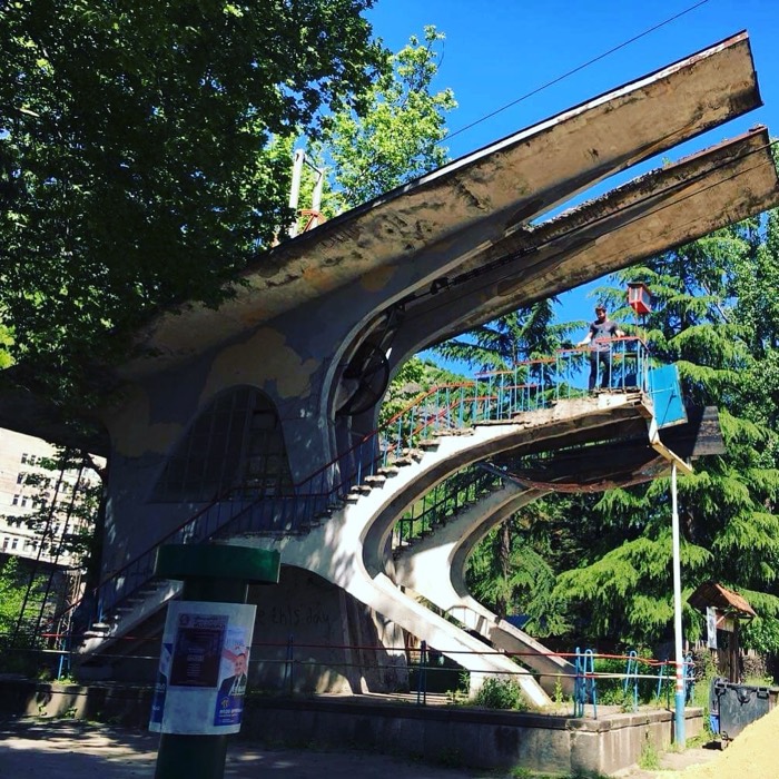 Brutalist Soviet curving staircase structure with figures, deep blue sky