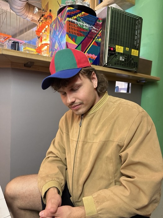 Joshua: in a colorful cap and tan jacket at a bar
