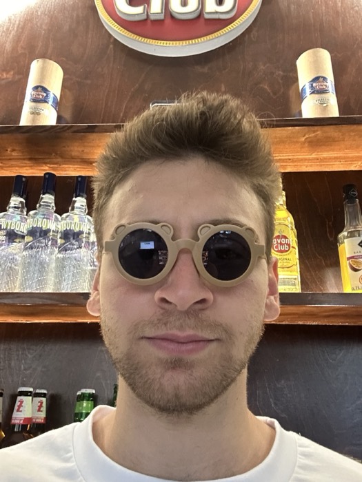 Joshua: bear-shaped sunglasses selfie at bar with Havana Club spirits behind