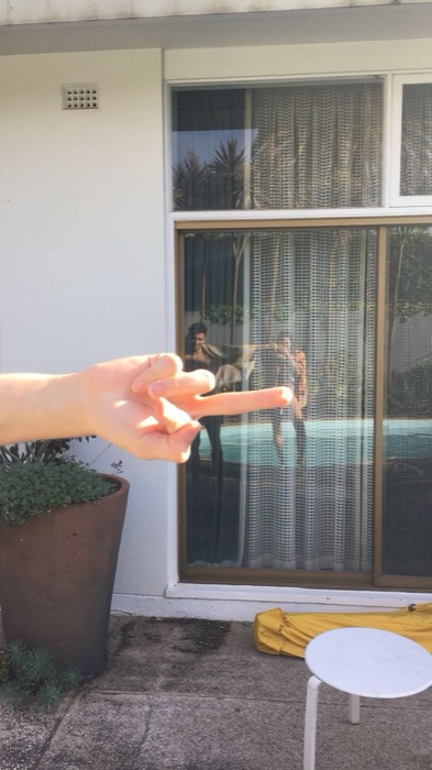 Peace sign and pool reflection at a mid-century motel courtyard.