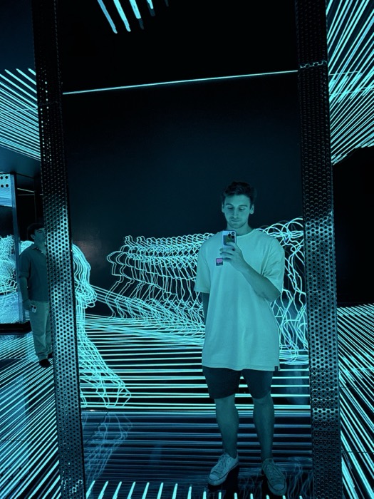 Joshua: near-identical solo mirror selfie in teal neon installation.