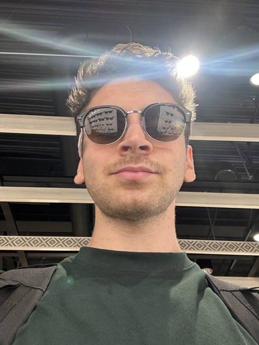 Joshua: sunglasses selfie under bright lights, possibly at an airport