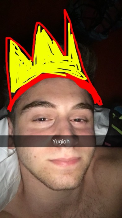 Joshua: dark bed selfie with Snapchat 'Yugioh' doodled crown.