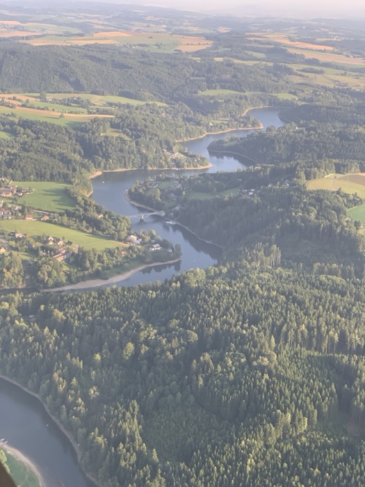 Aerial view of winding river, reservoir and forested hills from above
