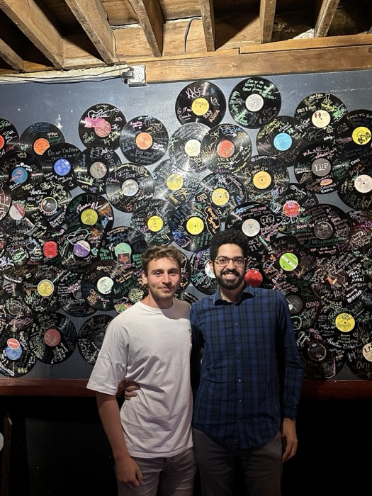 Joshua: with a friend before a wall of signed vinyl records
