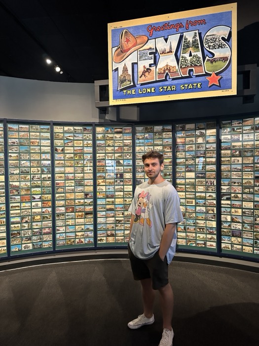 Joshua: posing before a wall of vintage Texas postcards in museum