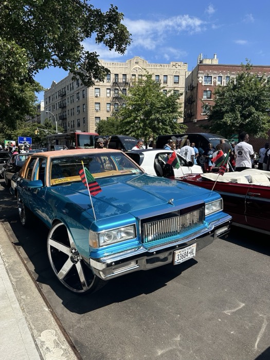 Blue lowrider Caprice on huge rims with flags at street car show