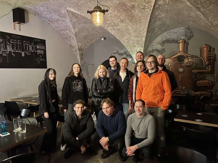 Group photo in a vaulted cellar bar with a copper still