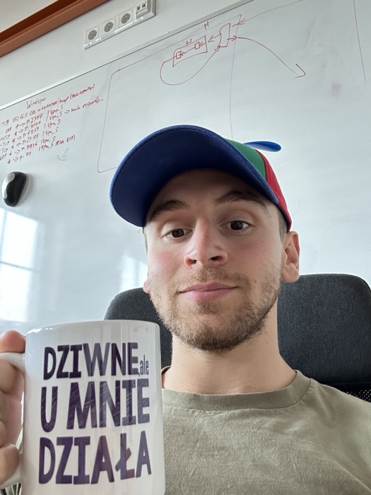 Joshua: selfie with mug, cap, in front of network-diagram whiteboard
